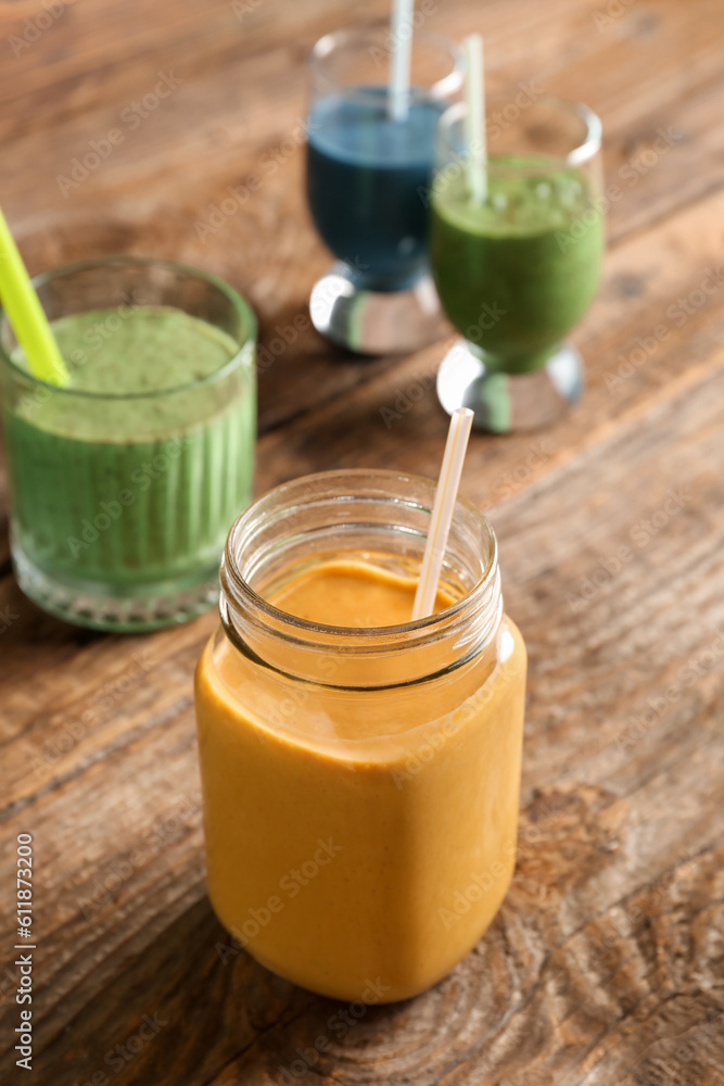 Mason jar of yellow smoothie on wooden background Mason jar of yellow smoothie on wooden background