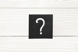 Paper with question mark on white wooden background