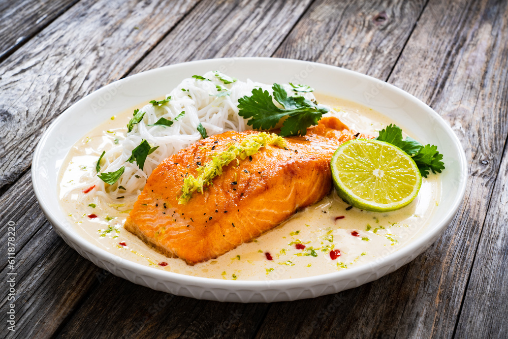 Creamy coconut lime salmon with rice noodles on wooden table Creamy coconut lime salmon with rice noodles on wooden table