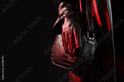 Attractive young woman in leather glove with bag on dark background, closeup