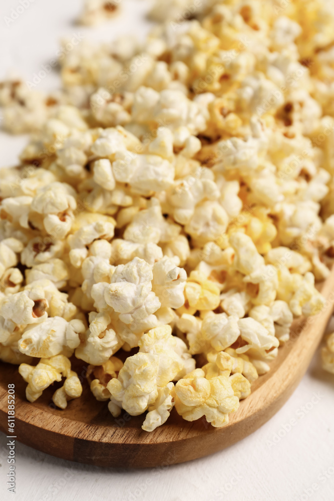 Wooden board with crispy popcorn on light background