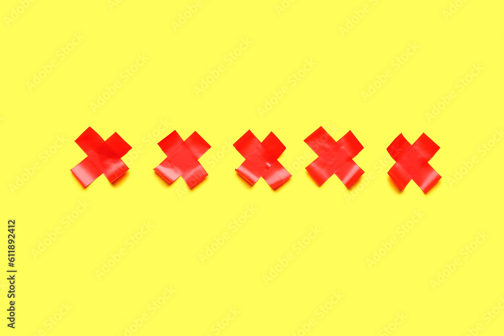 Obraz premium Red crosses made of adhesive tape on yellow background
