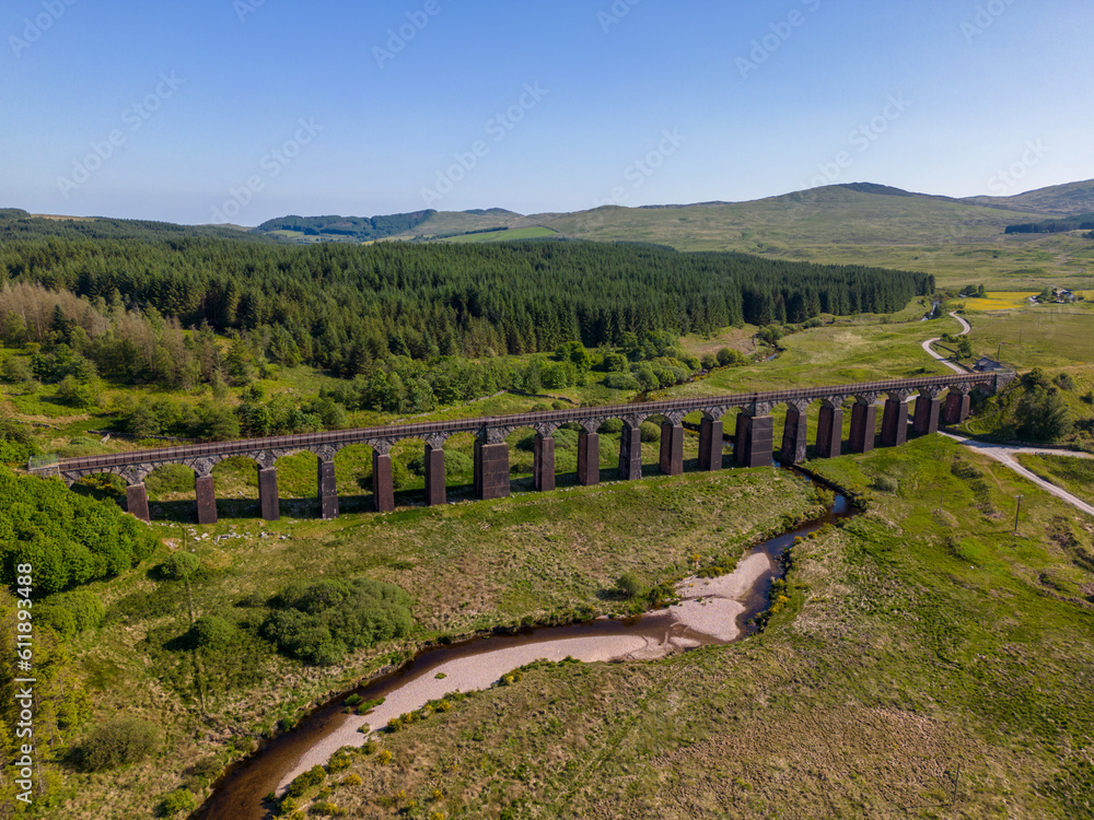 This aerial drone photo shows an old railway bridge. The bridge can be found in Galloway Forest National Park, Scotland. It is a beautiful forest where you can go hiking. 