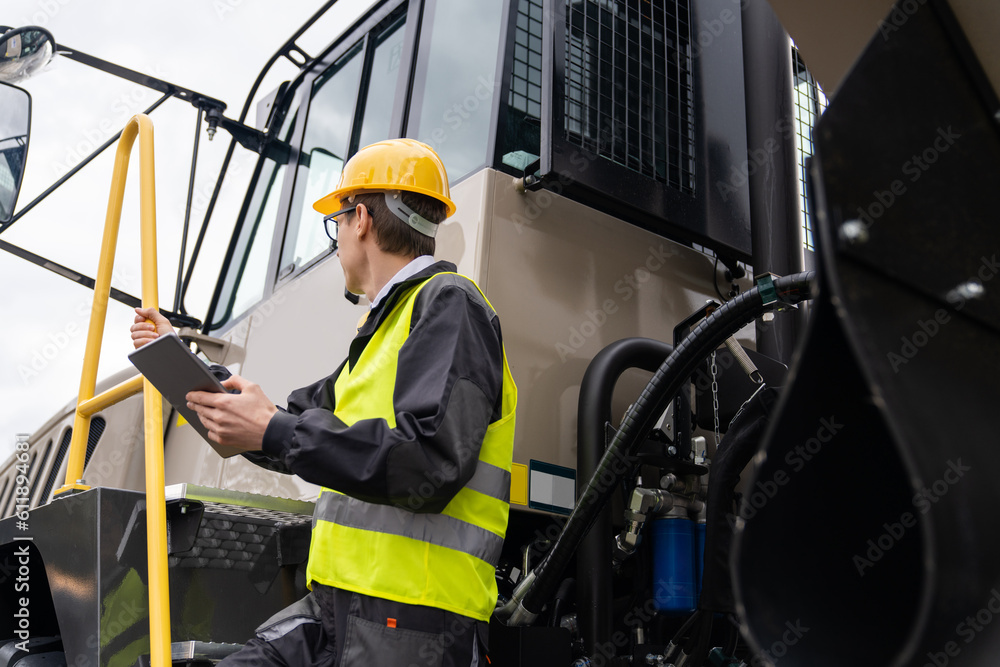 Engineer with tablet computer stands on the stairs to the cab of a truck Engineer with tablet computer stands on the stairs to the cab of a truck