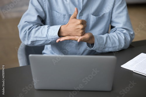 Hands of young man with hearing disability talking on video call with hand signs, showing gestures at laptop display, webcam, using service, smart application for patient with deafness. Cropped shot photo