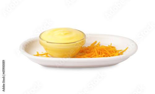 Plate with bowl of tasty cheddar sauce and grated cheese on white background