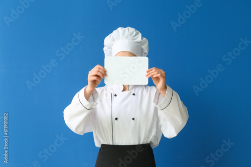 Female chef holding blank card on blue background