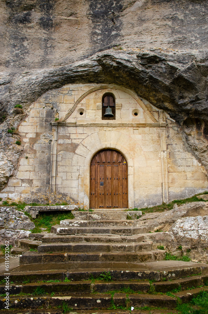 Archaeological natural monument and karstic complex Cueva Ermita de San Bernabé carved houses and church in a stone mountain. Merindandes region in Spain. 