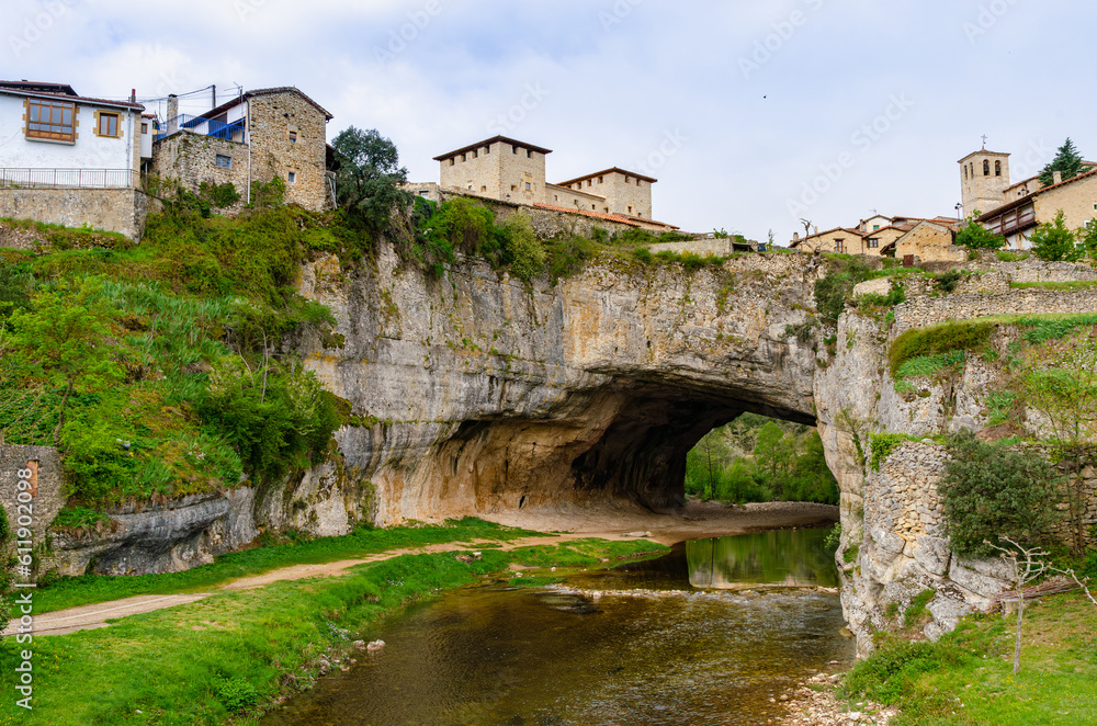 Natural bridge in the village Puentedey formed by a flowing river. Tunnel within rock underneath a village in Spain. 