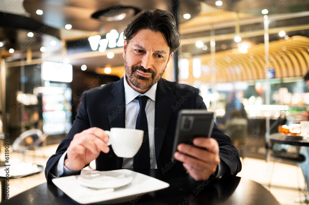 Manager having a coffee in a cafe while browsing his smartphone