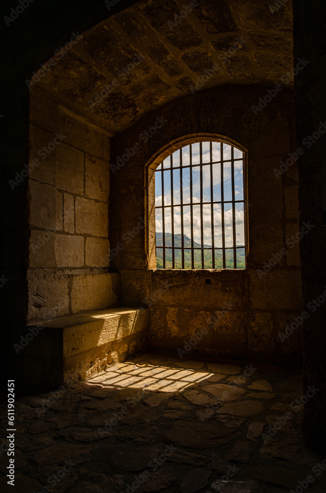 A dark prison room with bars preventing escape. Cold tower in castle in Spain. Cold stone walls.