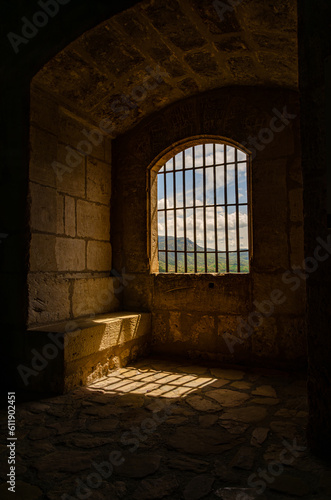A dark prison room with bars preventing escape. Cold tower in castle in Spain. Cold stone walls.