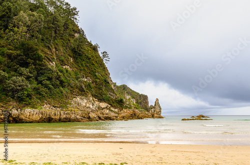 Sandy beach with a rocky hill reaching out to the sea.