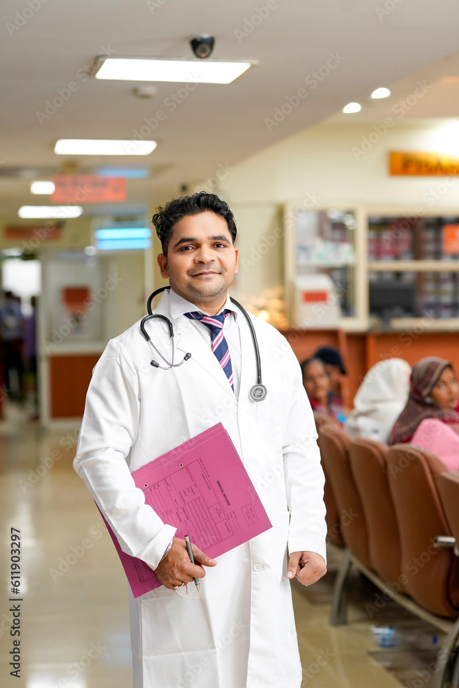 Indian male doctor holding file in hand and standing at hospital.