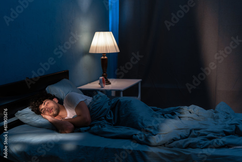 Young arabic man sleeping in bed at home at night. People, bedtime and rest concept photo
