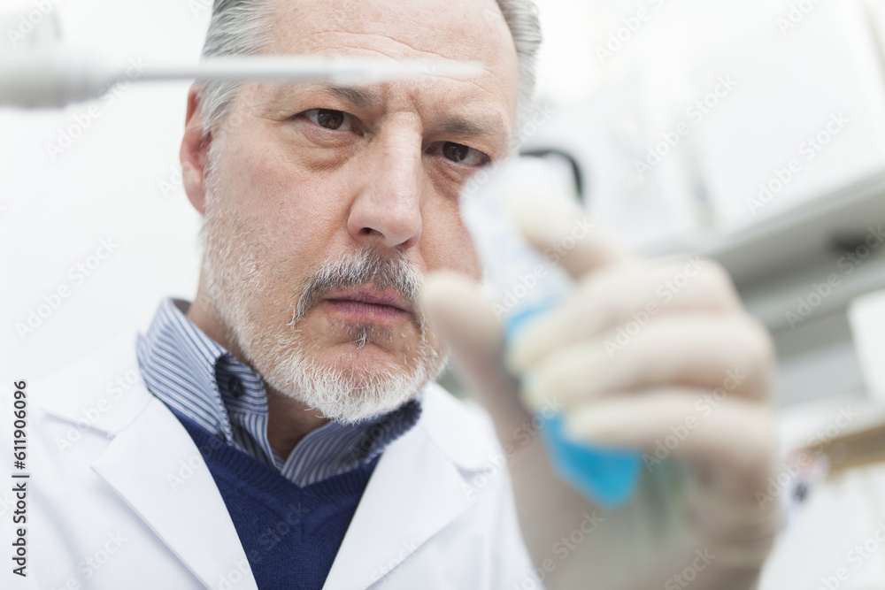 Close-up portrait of a male researcher holding flask with blue liquid in the lab Close-up portrait of a male researcher holding flask with blue liquid in the lab
