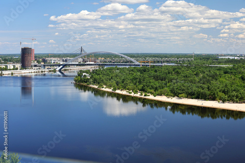 Summer landscape with a view of the Dnipro River, the beach coastline and several bridges over the river.