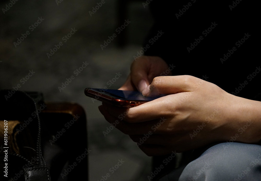 Business Woman’s hand typing on a phone in the shade