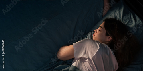 Top view of young woman sleeping in her bed at night. Girl sleeping with closed eyes.