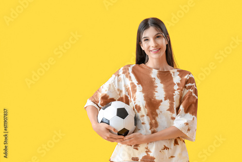 Fototapeta Naklejka Na Ścianę i Meble -  Young woman with soccer ball on yellow background