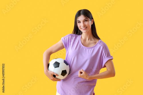 Sporty young woman with soccer ball on yellow background © Pixel-Shot