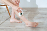 A woman using an epilator to remove unwanted leg hair at home.