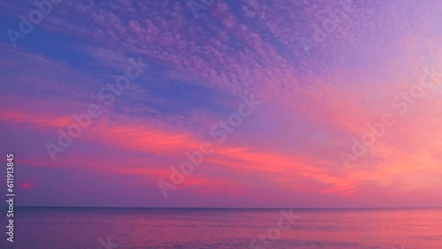Beautiful rippled sea waves on the purple and red sunrise sky background. Calm scene with view horizon on color glowing sky with clouds, mid shot, tilt up, real time, hd. ProRes 422 HQ.