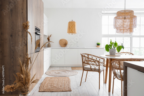 Interior of light kitchen with built-in oven, table, chairs and white counters
