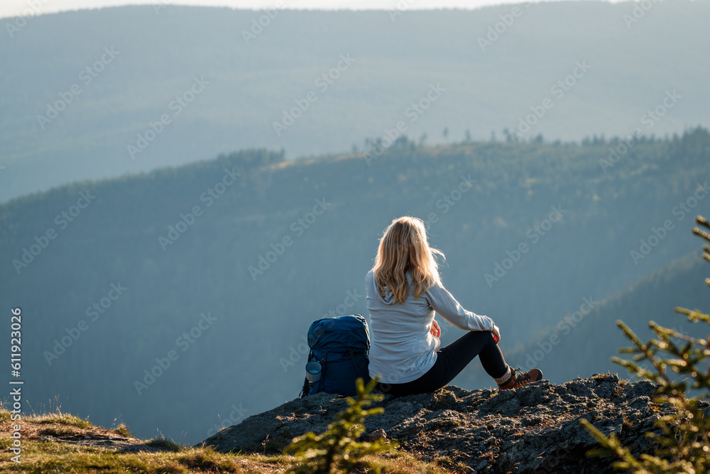 Woman with backpack relax on rock after successfully climbed mountain summit