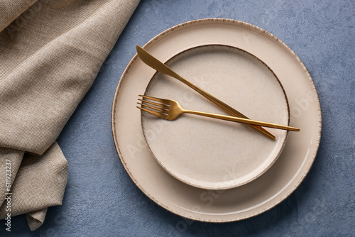 Tableau sur toile Golden fork with knife, plates and kitchen towel on blue grunge background