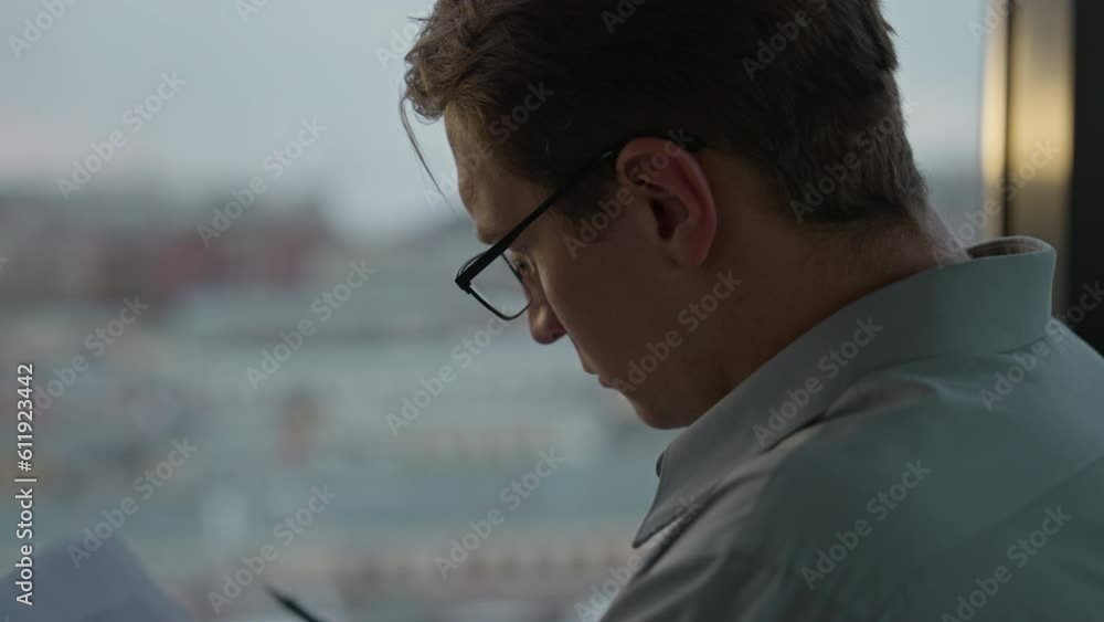 Businessman works responsibly with paper sitting by window in office