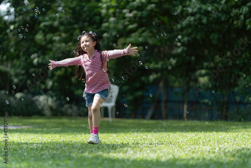 Asian girl chasing bubbles in the park.