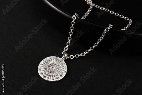 Plate with beautiful chain necklace on black background