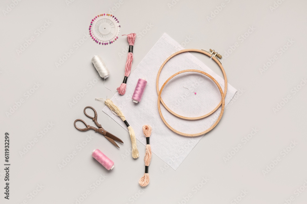 Wooden embroidery hoops with canvas, mouline threads and scissors on grey background Wooden embroidery hoops with canvas, mouline threads and scissors on grey background
