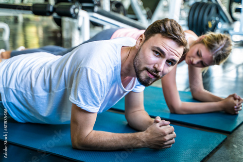 Fototapeta Naklejka Na Ścianę i Meble -  Smart man and woman buddy doing push up exercises and planking at indoor physical fitness