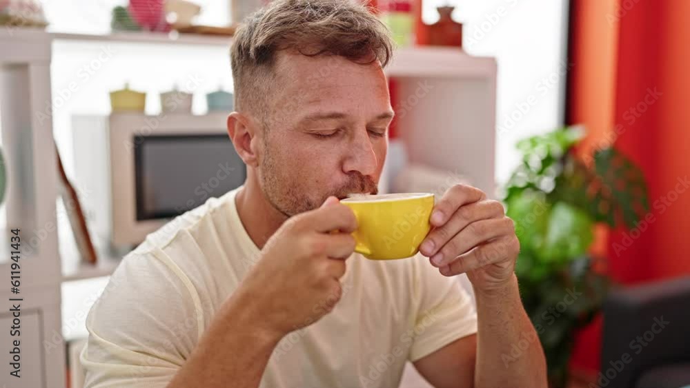 Young man drinking coffee sitting on table at dinning room Young man drinking coffee sitting on table at dinning room