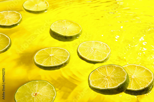 Slices of fresh lime in water on yellow background