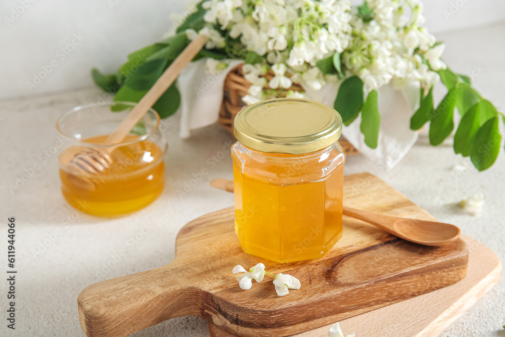 Jar of honey with flowers of acacia on light background, closeup Jar of honey with flowers of acacia on light background, closeup