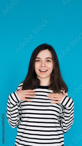 Portrait of a gorgeous  pretty  imposing girl in a striped pullover with her arms across her chest  isolated on a blue background.