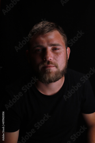 Thoughtful young bearded man on black background