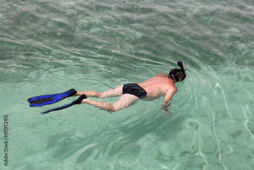 Man in scuba mask swimming in transparent sea water. Snorkeling and diving, beach vacation in summer