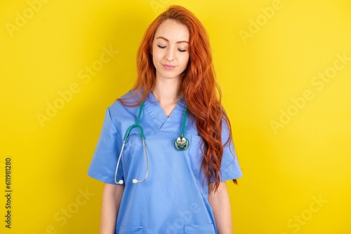 young red-haired doctor woman over yellow studio background nice-looking sweet charming cute attractive lovely winsome sweet peaceful closed eyes
