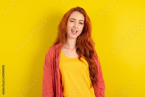 young beautiful red haired woman winking looking at the camera with sexy expression, cheerful and happy face.