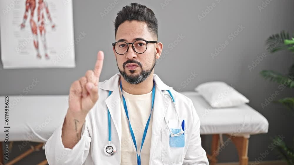 Young latin man doctor saying no with finger at clinic Young latin man doctor saying no with finger at clinic