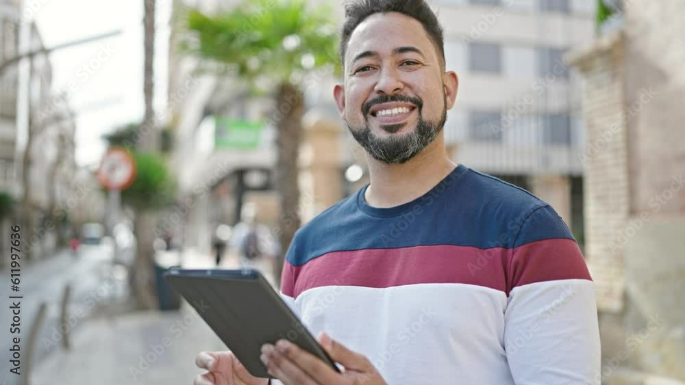 Young latin man smiling confident using touchpad at street Young latin man smiling confident using touchpad at street