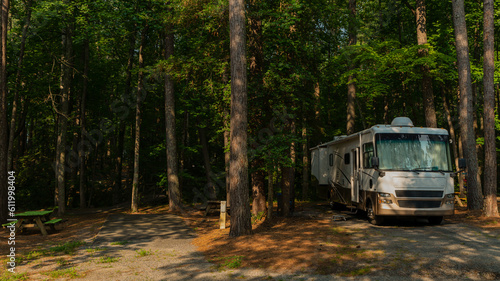 Rv motorhome parked at campsite with tall trees in forest