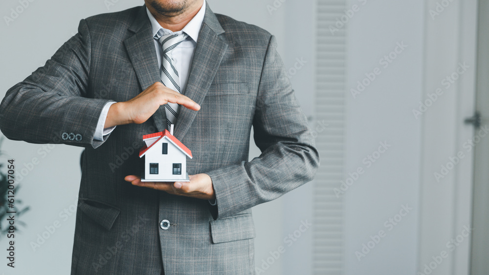 Property insurance and security concept. Protecting gesture of man and symbol of house. Estate agent giving house keys to woman and asked customer to sign the documents to make the contract legally. Property insurance and security concept. Protecting gesture of man and symbol of house. Estate agent giving house keys to woman and asked customer to sign the documents to make the contract legally.