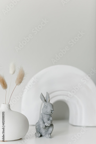 Creative composition of living room interior with copy space  stylish vase  wall with stucco.Home decor. Template. Hygge scene with candles on white background. Bunny candle. Bubbles candle