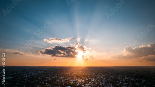 aerial view of sky with sun, clouds and sunbeams at sunset over the city © david