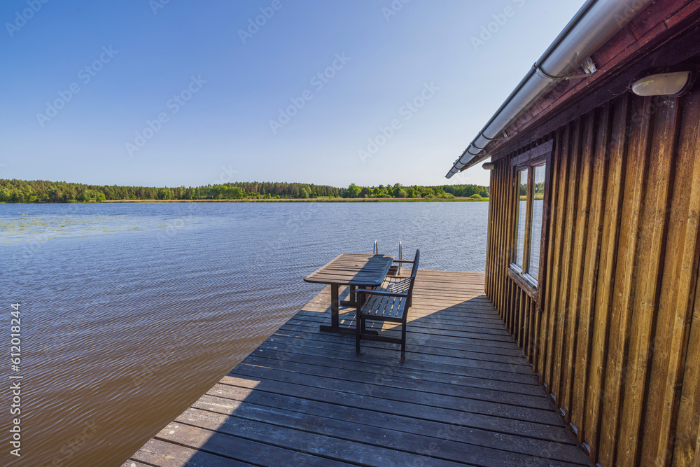 Beautiful view of backyard of villa located on lake with old wooden patio. Sweden.